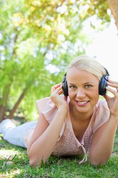 Smiling young woman with headphones enjoying music on the grass