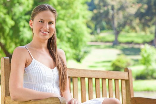 Smiling young woman on a park bench