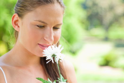 Young woman smelling on a white flower in the park