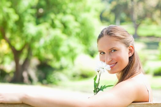 Side view of a smiling young woman smelling a flower