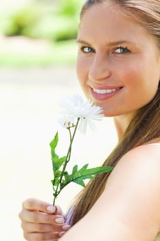 Close up of a smiling young woman smelling a flower