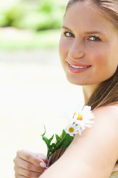 Close up of a smiling young woman with a flower