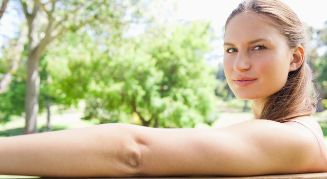 Side view of a young woman sitting on a park bench