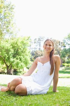 Smiling young woman in the park sitting on the lawn