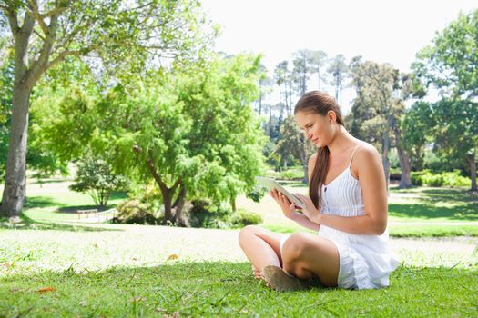 Side view of young woman on the lawn with her tablet computer