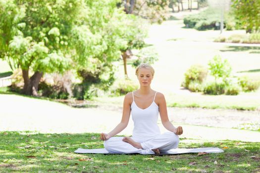 Young woman sitting in a yoga position on the lawn