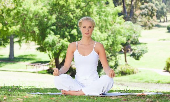 Young woman sitting on the meadow doing yoga exercises