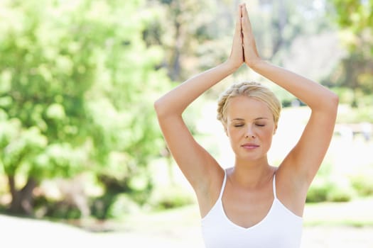 Relaxed young woman in a yoga position in the park