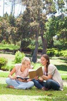 Young woman showing her friend something in her book