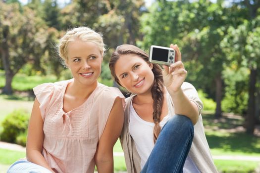 Female friends taking pictures on themselves with a camera