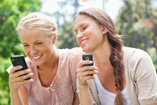 Smiling female friends with cellphones