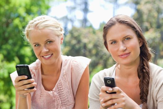 Female friends with their cellphones in the park