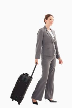 A smiling businesswoman with a suitcase is walking