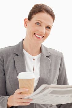 Smiling businesswoman holding newspaper and cup