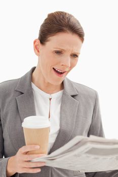 A surprised businesswoman is reading the newspaper