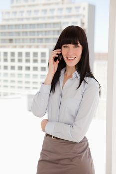 A woman in a sharp business suit at work making a call