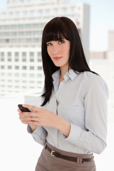 A business woman looks in front of her as she sends a text from her mobile phone