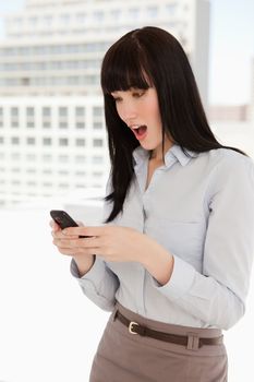 A shocked woman reading a text message from her phone while at work