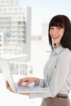 A business woman with a laptop in her hands laughs while at work