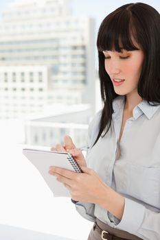 A woman holding a note pad in her hands as she writes on it
