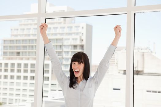 A celebrating business woman with her arms raised up in the air