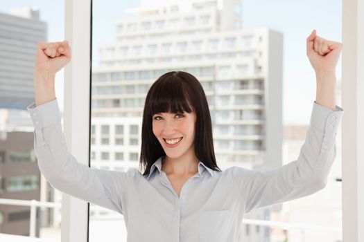 A happy business woman with her arms raised above her head in celebration