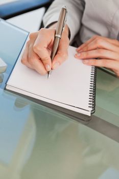 A close up shot of a woman taking down some notes on a notepad