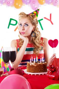 Surprised pinup girl sitting at party table with baloons over white