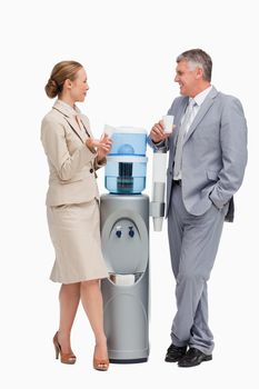 Business people laughing next to the water dispenser against white background