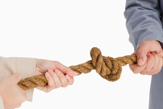 Business people tightening a knot against white background