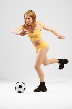 Young girl in yellow is going to kick a ball