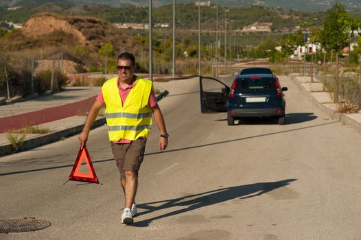 Guy carrying a triangle to warn of his breakdown