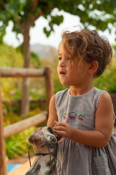 Portrait of a Hispanic girl enjoying her ride on an old horse toy