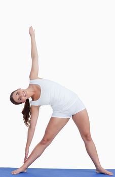 Smiling woman practicing yoga against a white backrground
