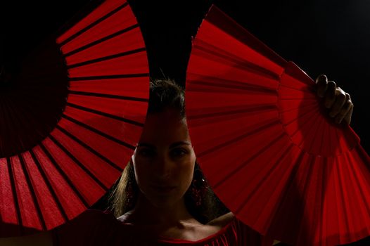 The sensuality of red fans framing the face of a flamenco dancer