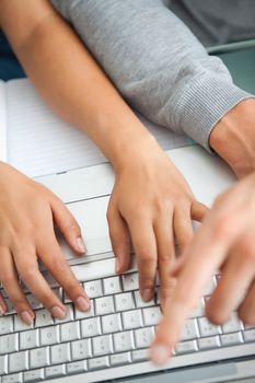 High view of students hands working with a laptop while typing and pointing the screen