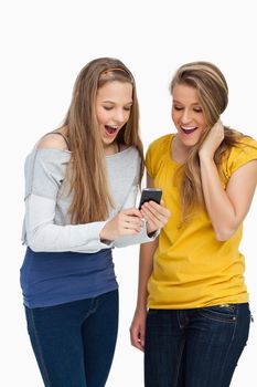 Two surprised students looking a cellphone screen against white background