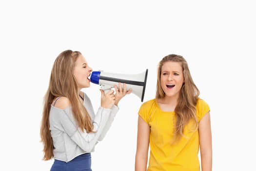 Female student using a loudspeaker on a other girl against white background