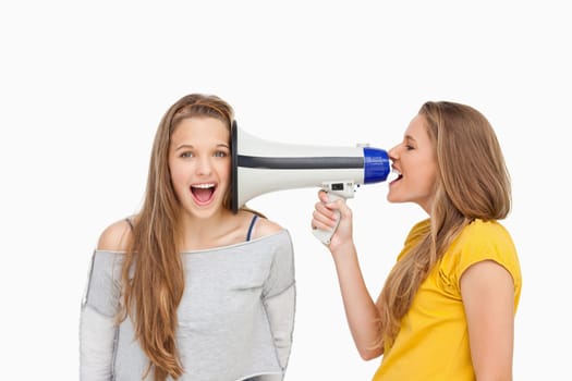 Blonde student using a loudspeaker on her friend against white background