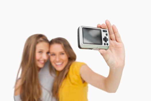 Two students taking a picture of themselves with a digital camera against white background