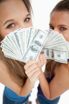 High-angle view of two young woman behind dollars against white background