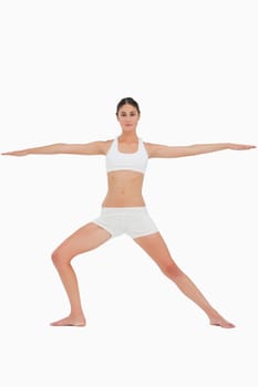Woman doing the yoga warrior pose against white background