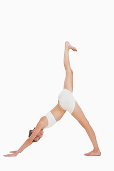 Woman doing yoga while looking at camera against white background