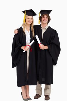 Two students in graduate robe shoulder to shoulder against white background