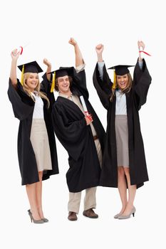 Three students in graduate robe raising their arms against white background