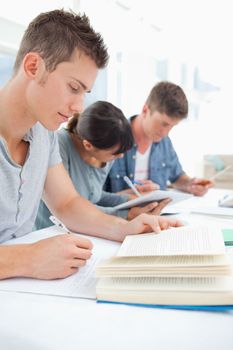 A close up shot of three students sitting together and studying 