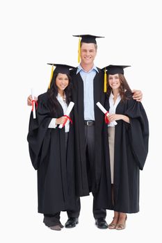 A full length shot of three graduating students looking into the camera 