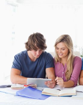 A smiling couple look at a tablet together as they sit at the table 