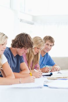 A close up of a student smiling while he sits with his friends as he then also looks into the camera