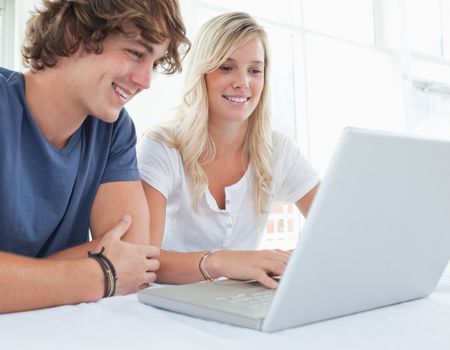 A smiling couple smiling as they look at the laptop in front of them 